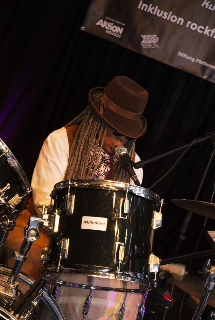 Foto: Musikerin am Schlagzeug singt beim Konzert von Handiclapped